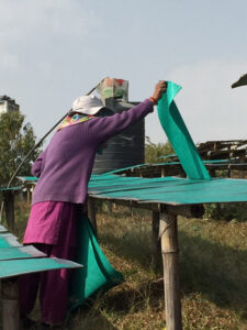 a snapshot of a woman viewing paper production in Nepal