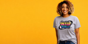 Smiling person wearing the NCTE "Proud to be Inter-Textual" t-shirt on a bright yellow background.