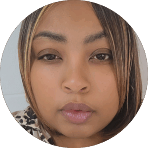 Circular portrait — young woman with shoulder-length brown hair with blonde highlights, neutral close-mouthed expression, wearing a leopard-print top, against a plain white wall